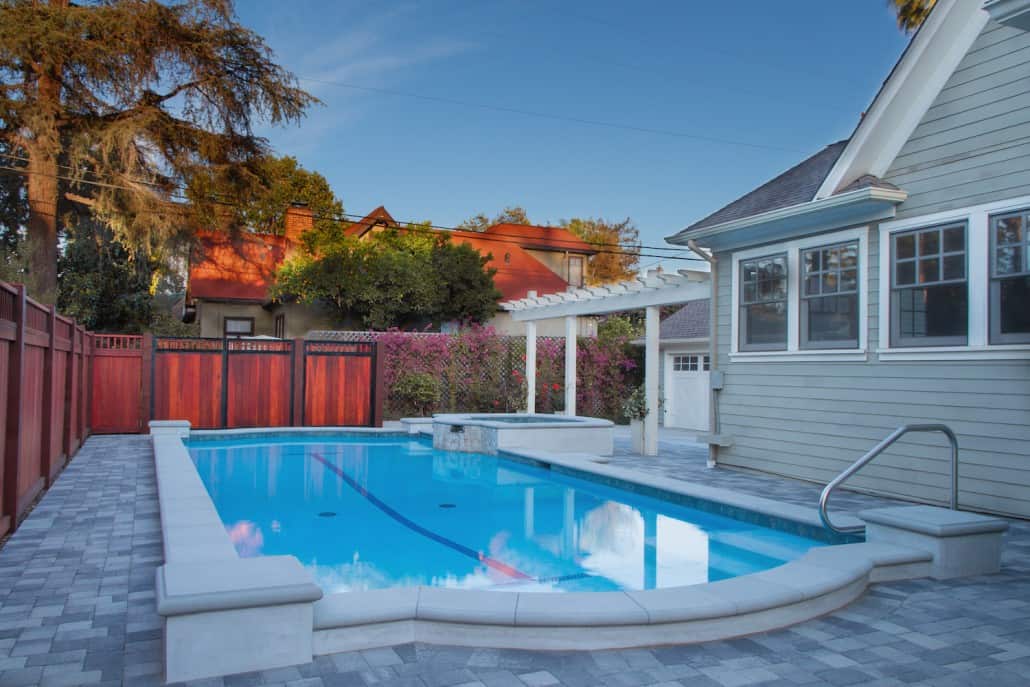 A large swimming pool is in the backyard of a house.