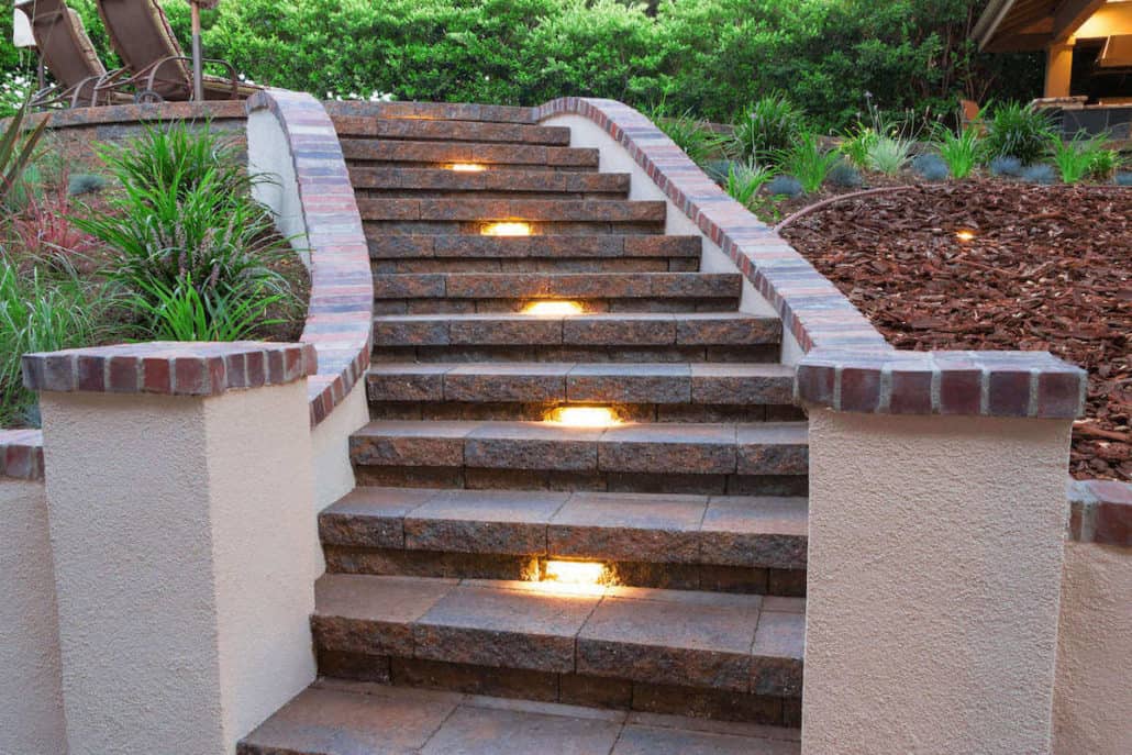 A set of stairs with lights on them leading up to a house.