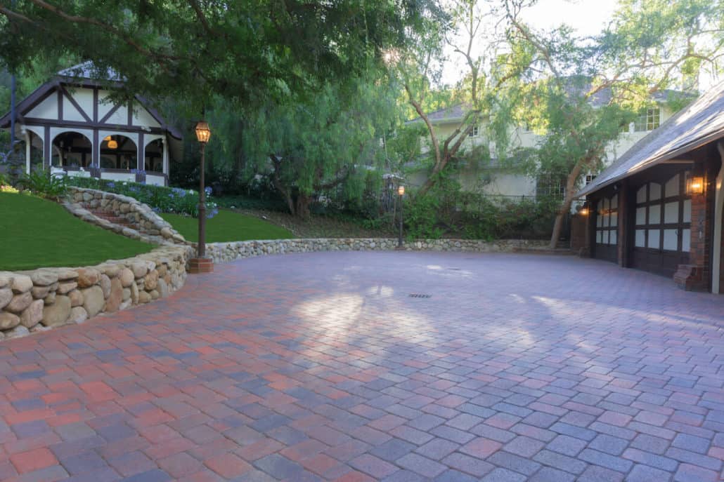 A brick driveway leading to a house with a garage.