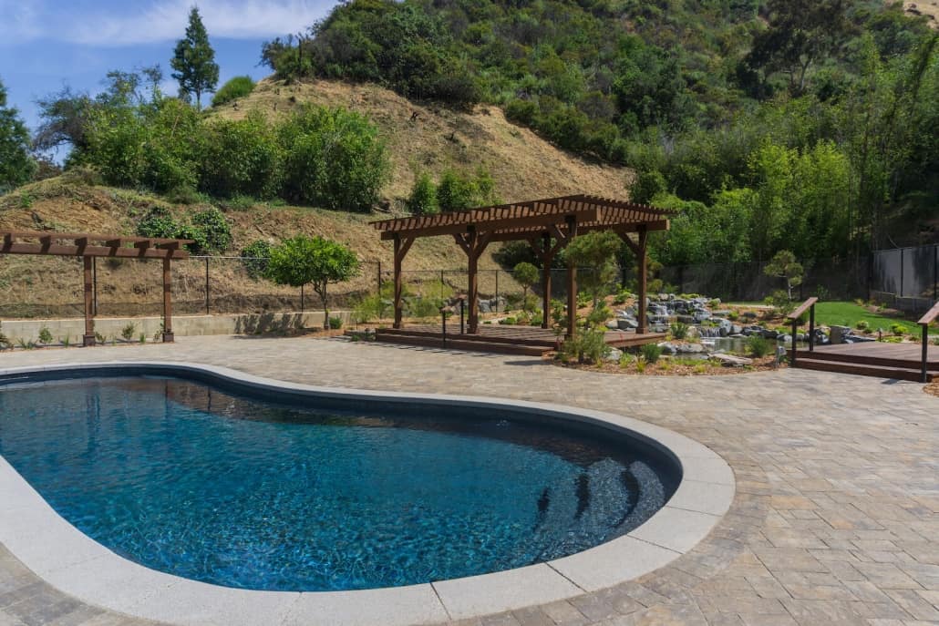 A large swimming pool with a pergola in the background