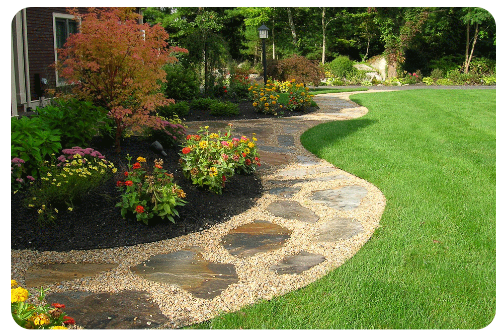 A stone walkway leading to a house in a lush green garden