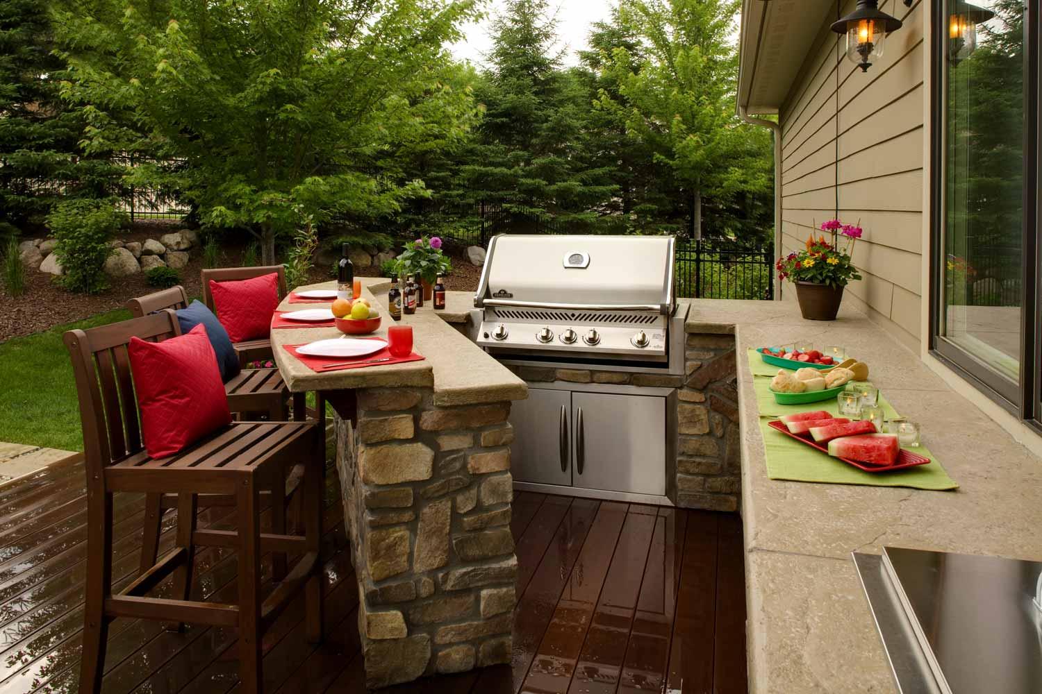 A patio with a grill and a table and chairs.