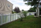 There is a white fence in the backyard of a house.