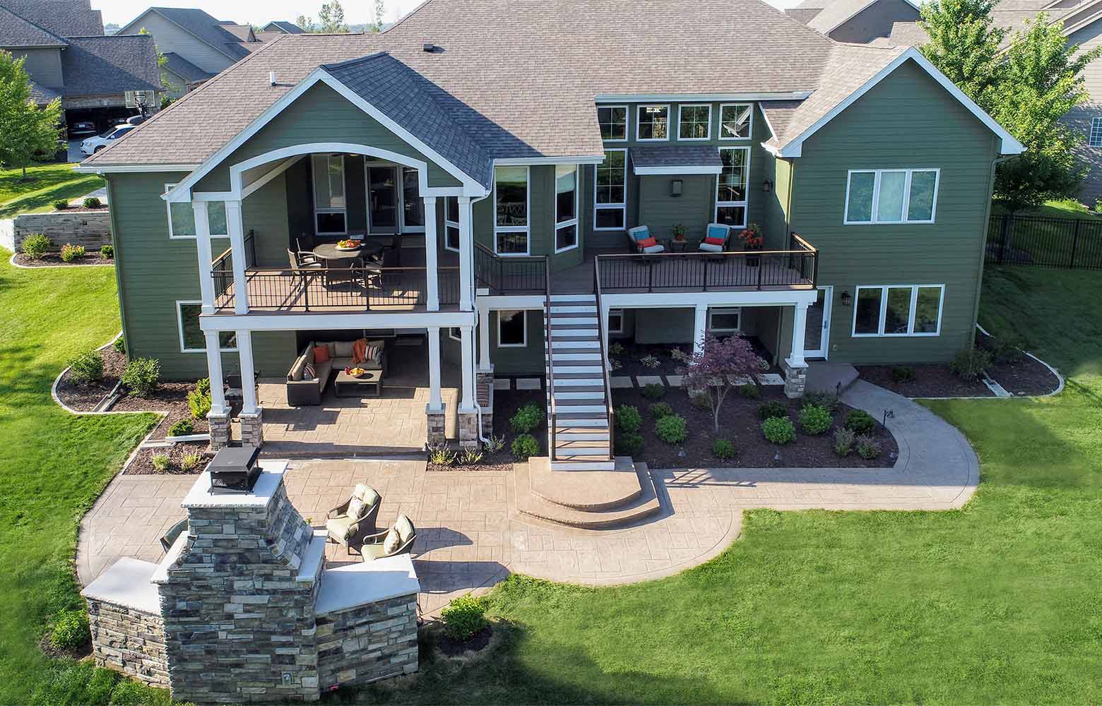 An aerial view of a large green house with a patio and fireplace.