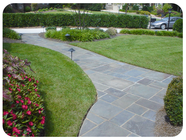 A stone walkway leading to a lush green lawn