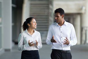 Happy Indian business colleagues walking outside office and talking