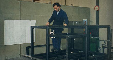 un operaio con tenuta blu vicino a un telaio assemblato a Piacenza