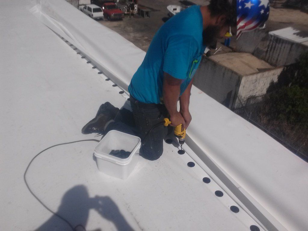 a man in a blue shirt is working on a white roof
