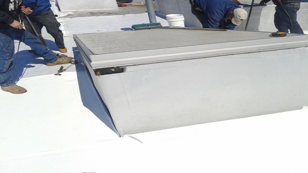 a group of men are working on a white roof