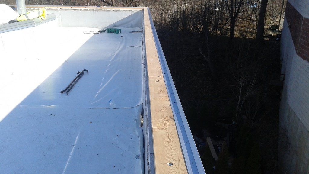 a white roof with a blue trim is being installed on a building .