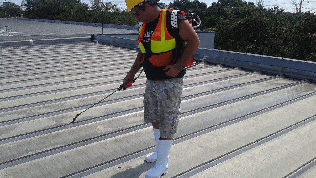 a man is spraying a roof with a sprayer .