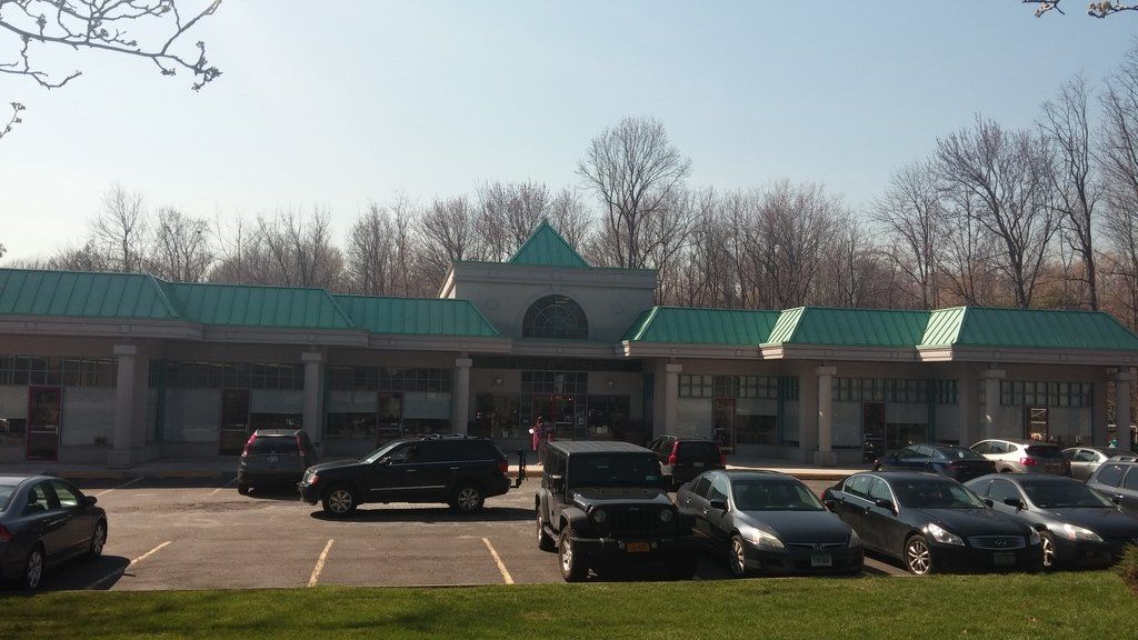 a row of cars are parked in front of a building with a green roof