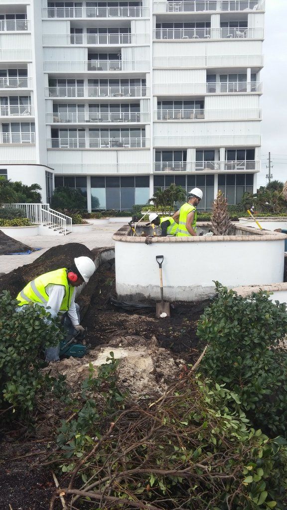 two construction workers are digging in the dirt in front of a building .