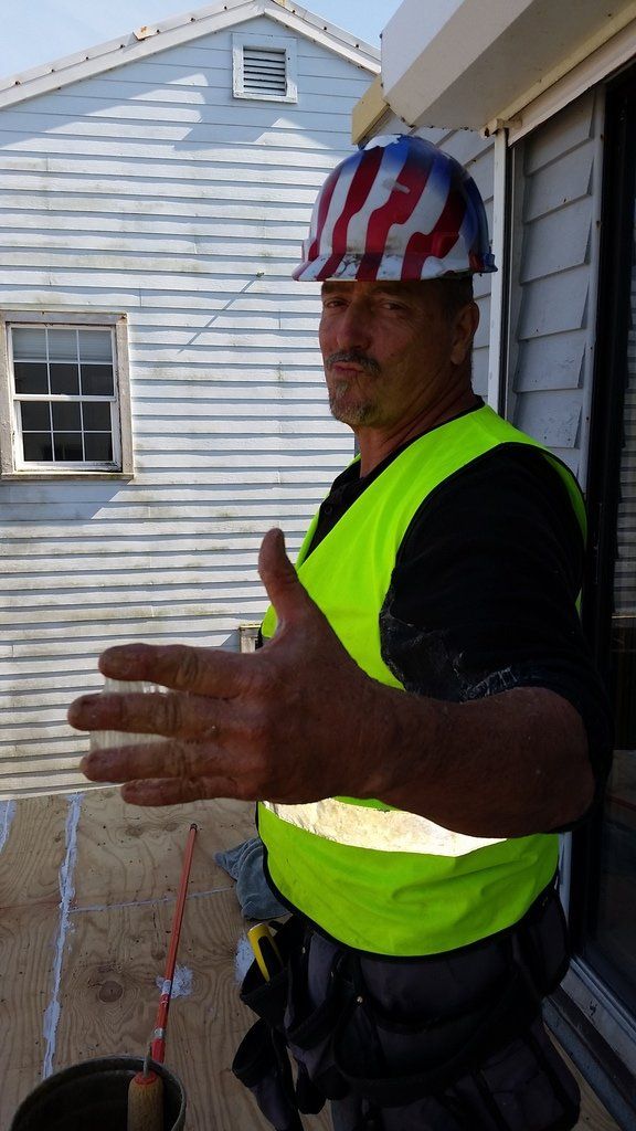 a man wearing a hard hat and a yellow vest is giving a thumbs up .