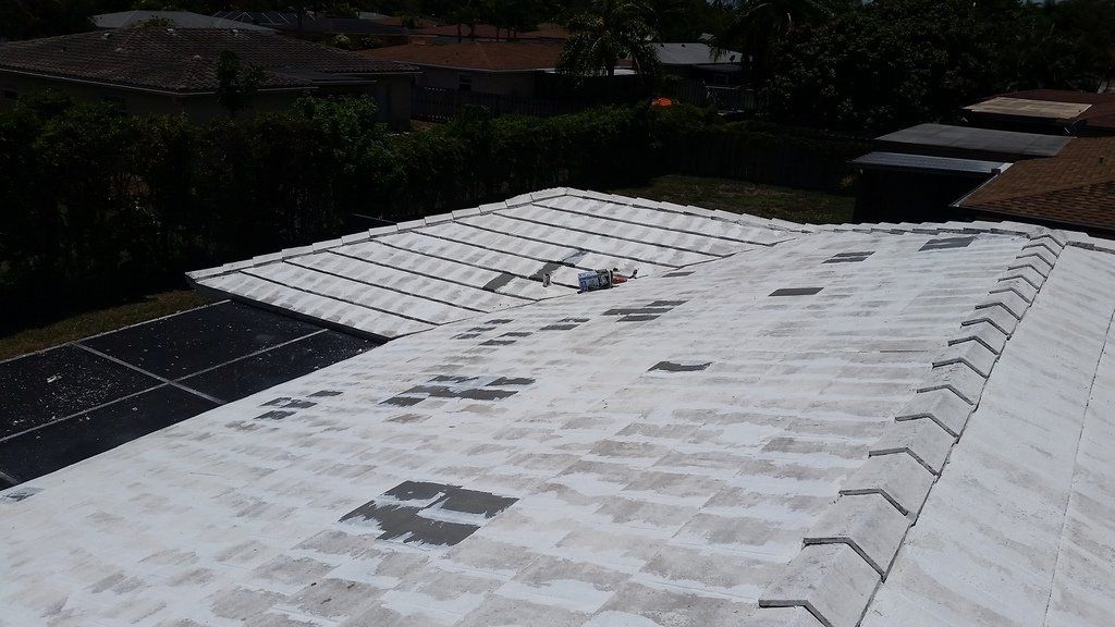 a roof with a lot of shingles on it is being painted white .