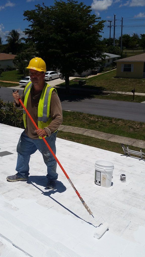a man is painting a roof with a roller .