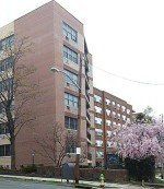 a large brick building with a lot of windows is sitting next to a street .