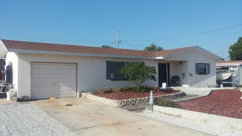 a white house with a brown roof and a driveway