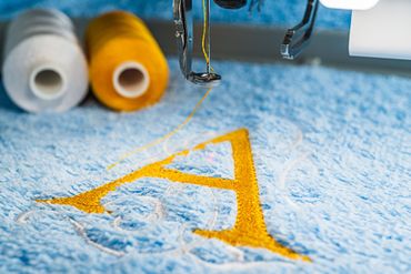 Embroidery machine stitching a gold letter 