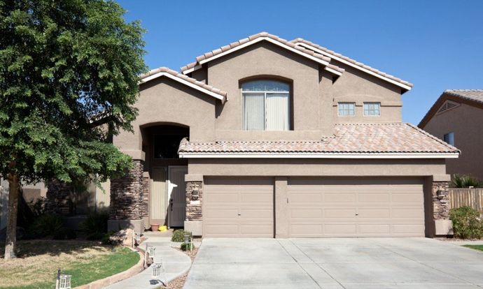 Two-story beige house with a three-car garage and a front lawn Two-story beige house with a three-car garage and a front lawn
