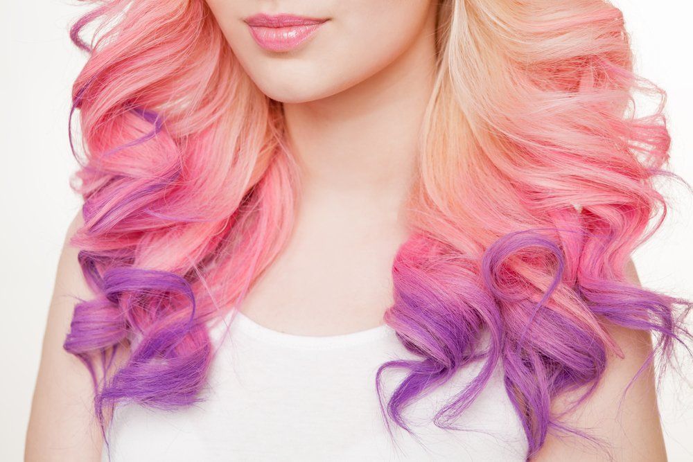 Eine Frau mit rosa und violettem Haar trägt ein weißes Hemd.