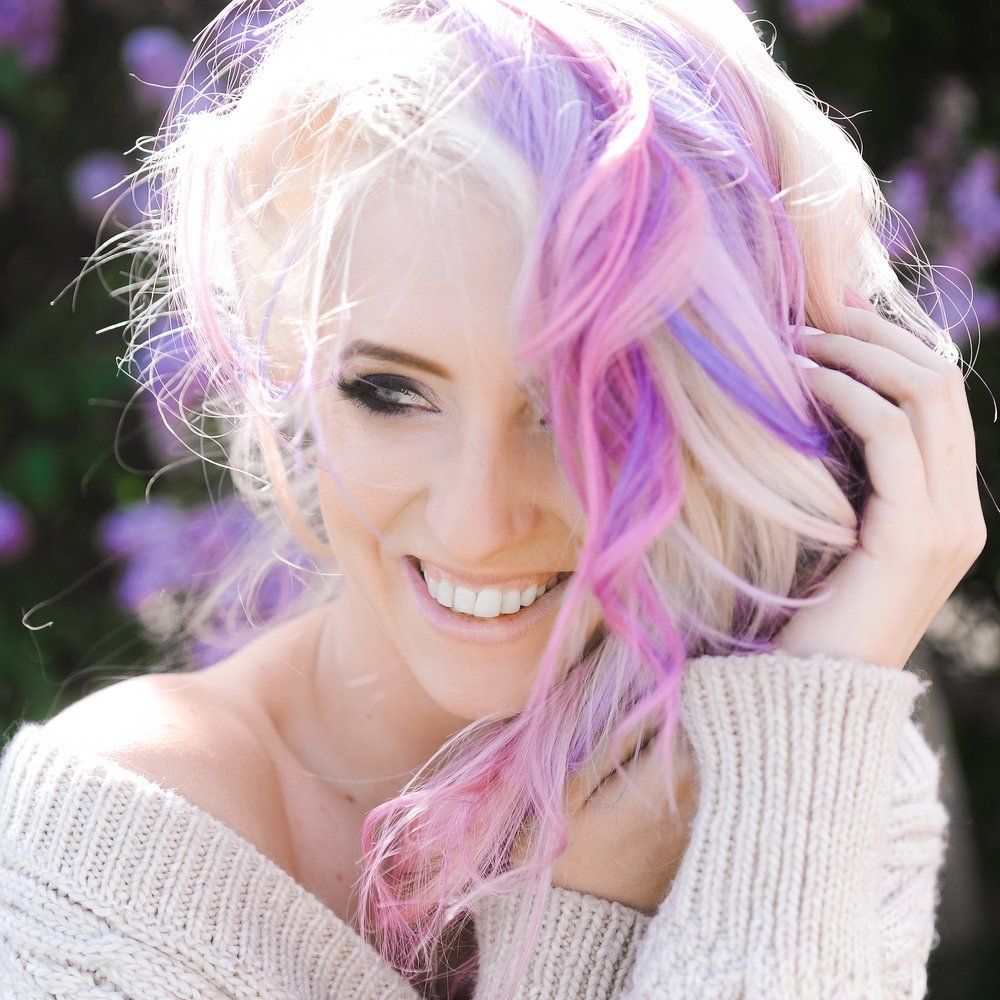 Eine Frau mit rosa und lila Haaren lächelt