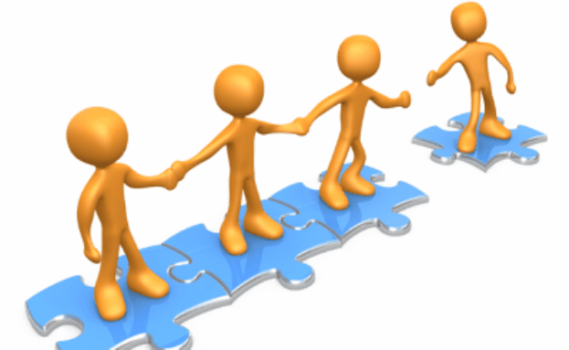 A group of people standing on puzzle pieces holding hands