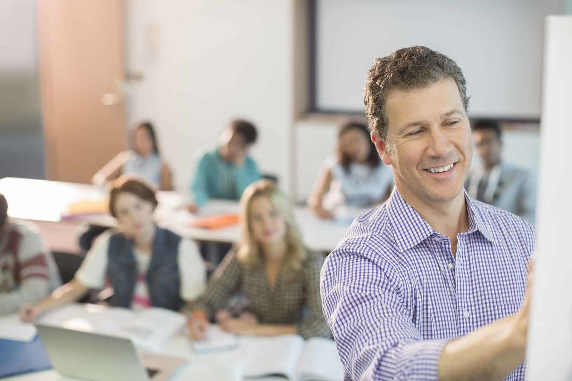 Teacher writing on whiteboard in classroom