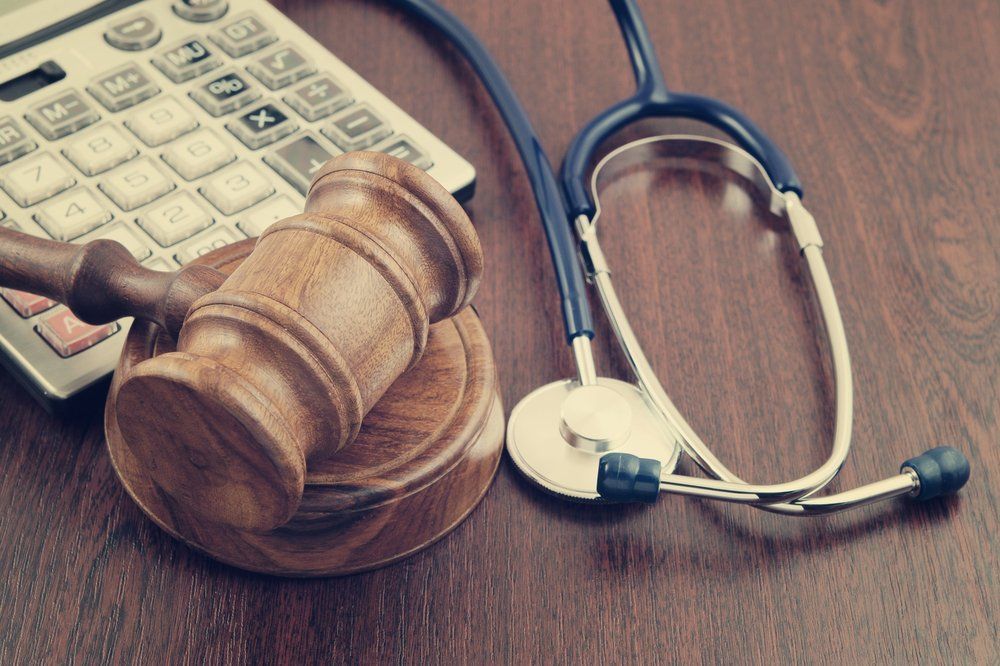 stethoscope sitting next to gavel and calculator on wooden table
