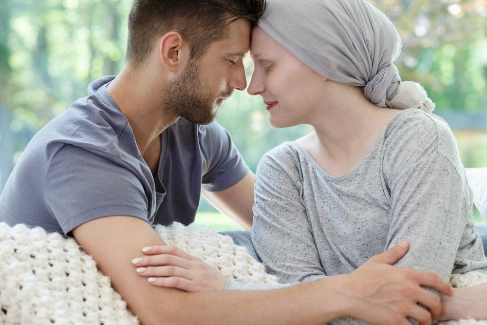 Handsome husband and young wife with cancer touching each other's heads