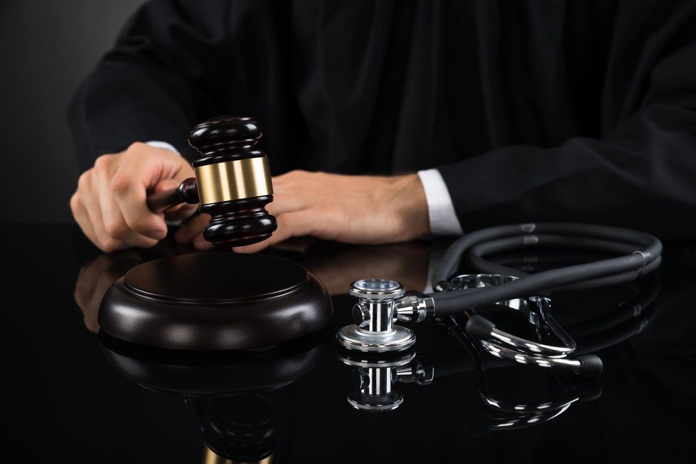 lose-up Of Judge Hands Hitting Gavel With Stethoscope In Courtroom