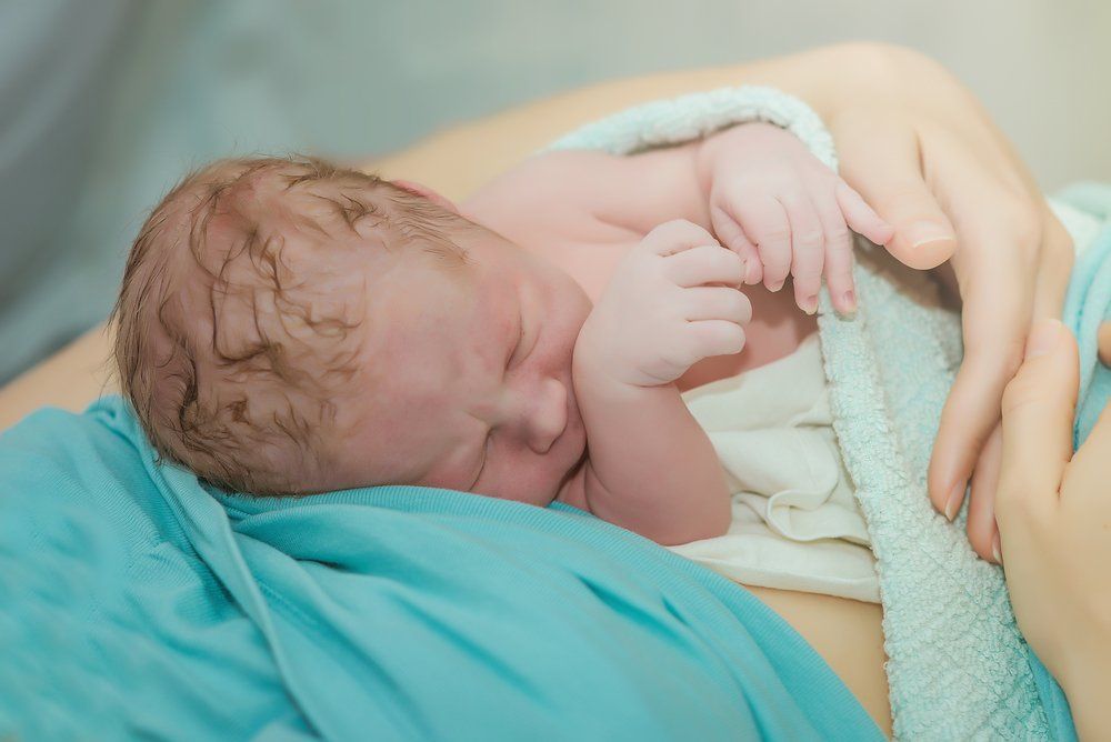 newborn baby being held by its mother 