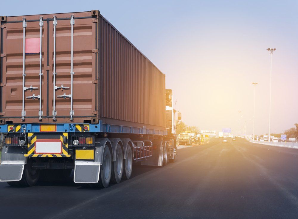 semi truck driving down the highway into the sunset 