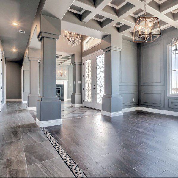 Elegant empty hallway with gray paneled walls, coffered ceiling, and dark wood floors