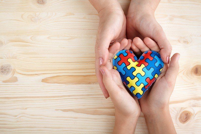 A couple of hands holding a heart made of puzzle pieces.