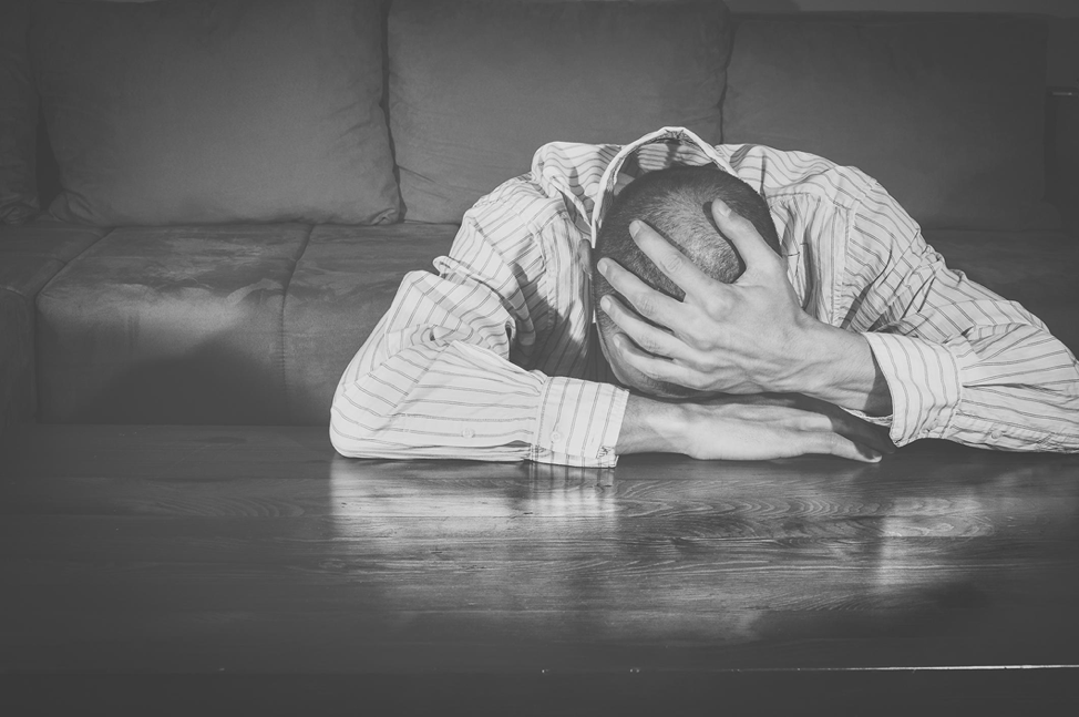 A man is sitting at a table with his head in his hands.