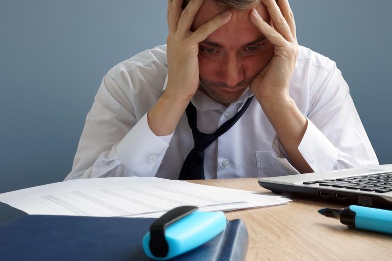 A man sitting at a desk with his hands on his head