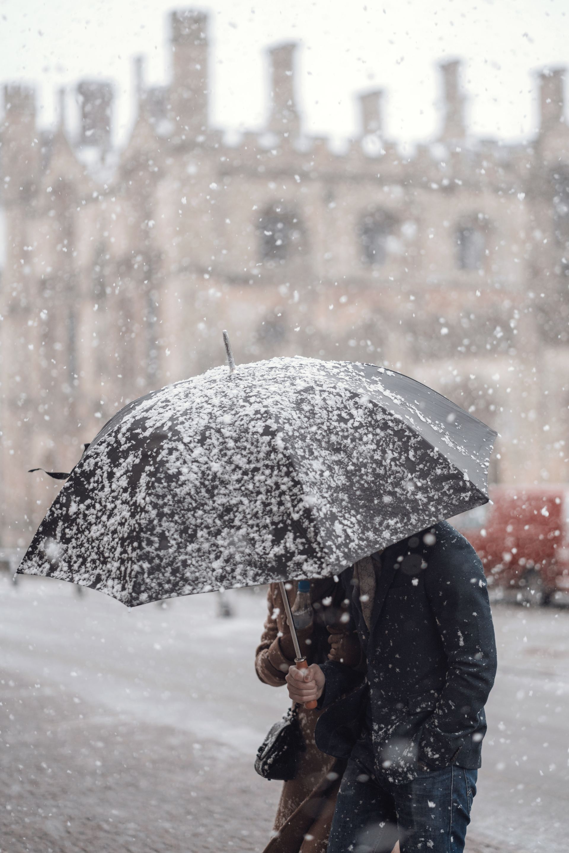 A man and woman holding an umbrella in the snow