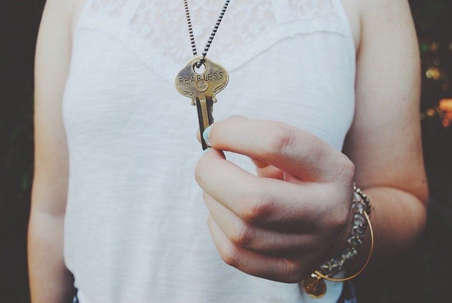 A woman in a white tank top is holding a key