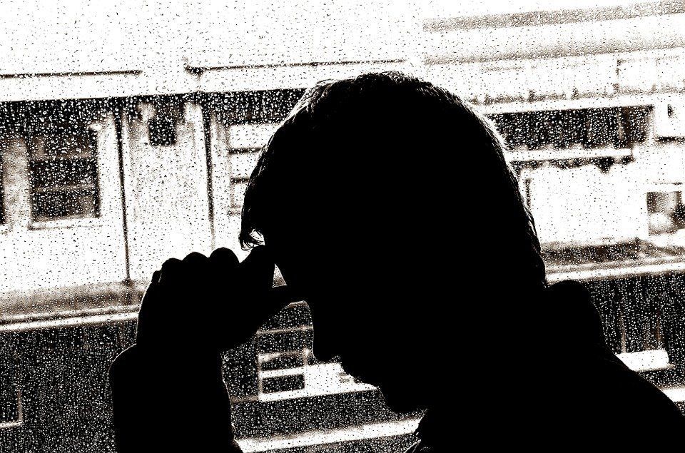 A silhouette of a person looking out a window with a train in the background.
