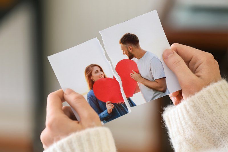 A woman is holding a broken photo of a man and a woman.