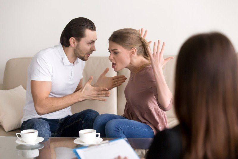 A man and a woman are sitting on a couch having an argument.