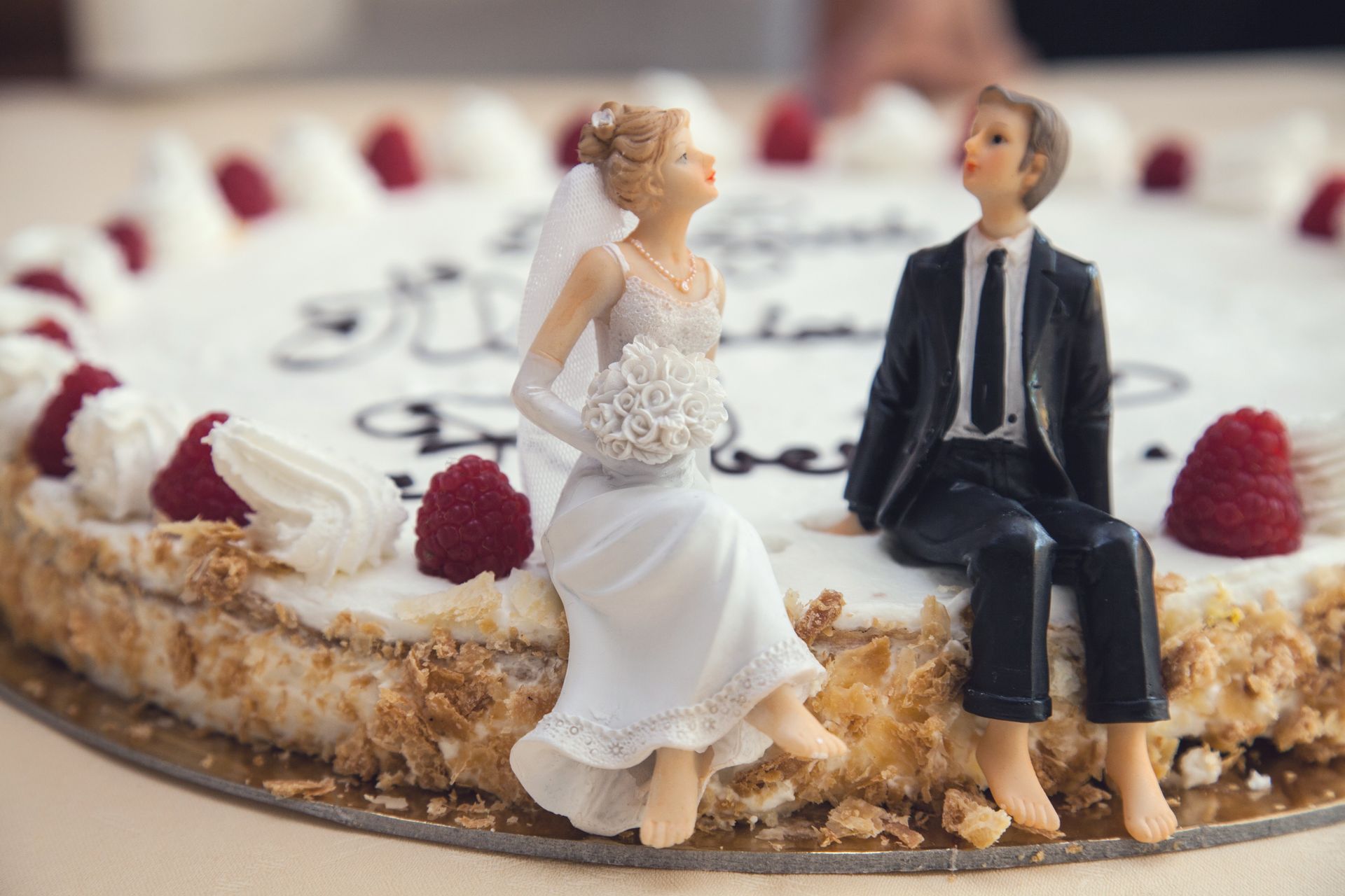 A bride and groom figurine are sitting on top of a wedding cake.