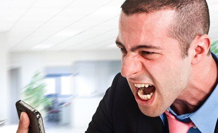 A man in a suit and tie is yelling at his cell phone.