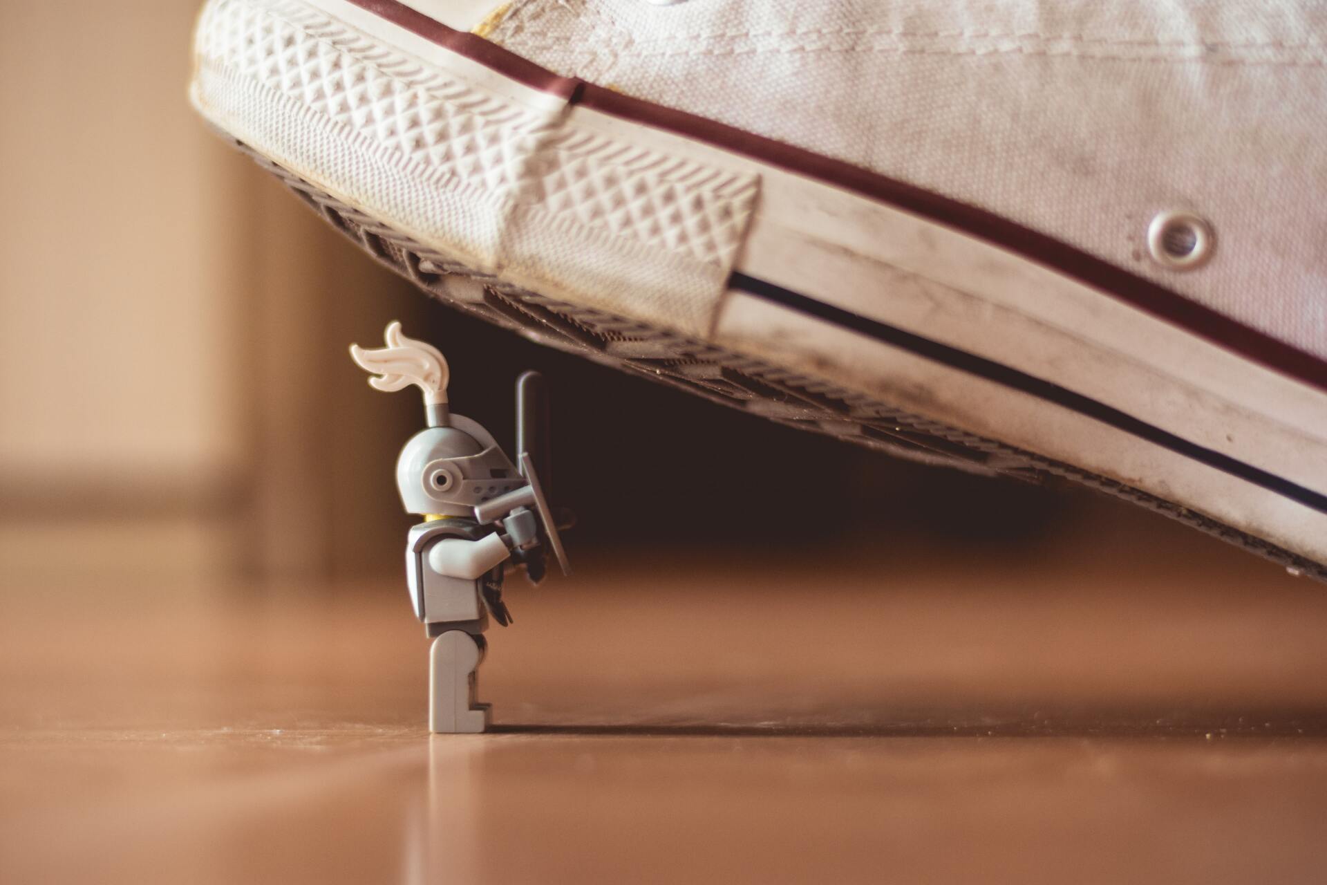 A lego knight is standing next to a person 's foot.