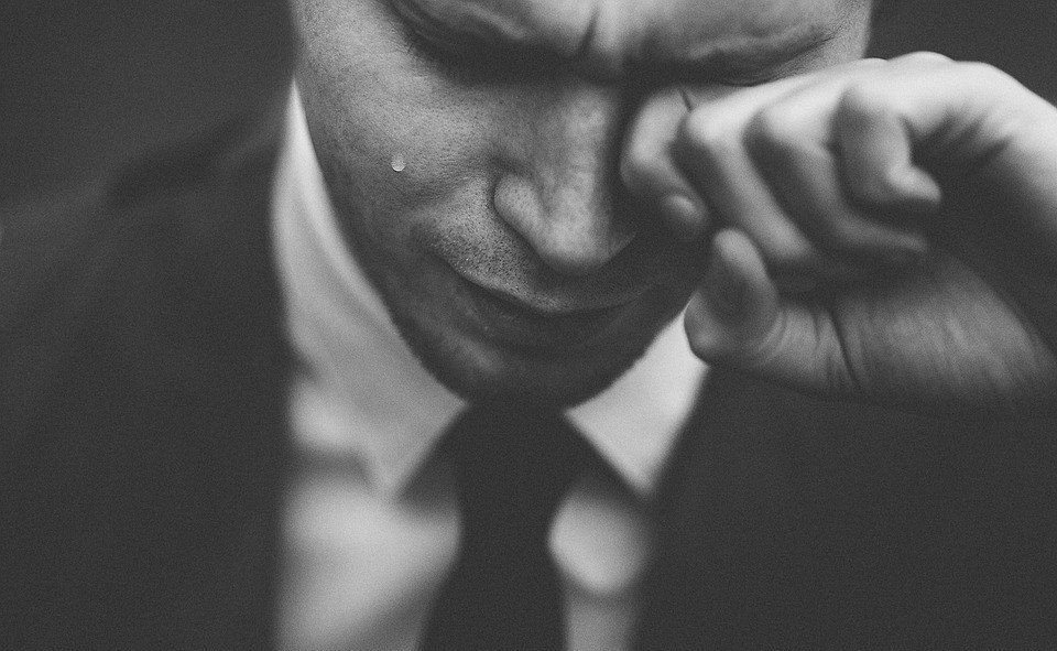 A man in a suit and tie is crying with a tear coming out of his eye.