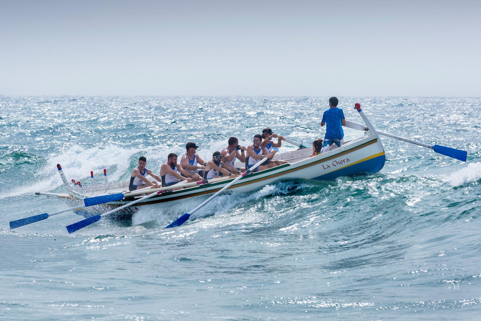 A group of people are rowing a boat in the ocean.