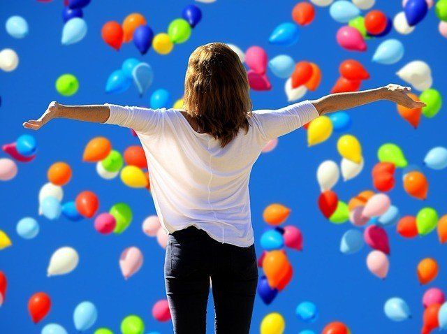 A woman is standing in front of a bunch of colorful balloons