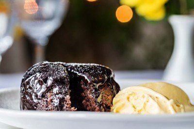 Molten chocolate lava cake with vanilla ice cream on a white plate, in a restaurant setting.