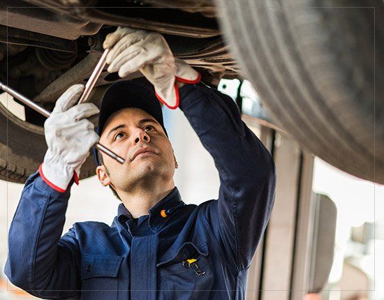 Mechanic repairing a lifted car - Auto Care in Gorham,ME Mechanic repairing a lifted car - Auto Care in Gorham,ME